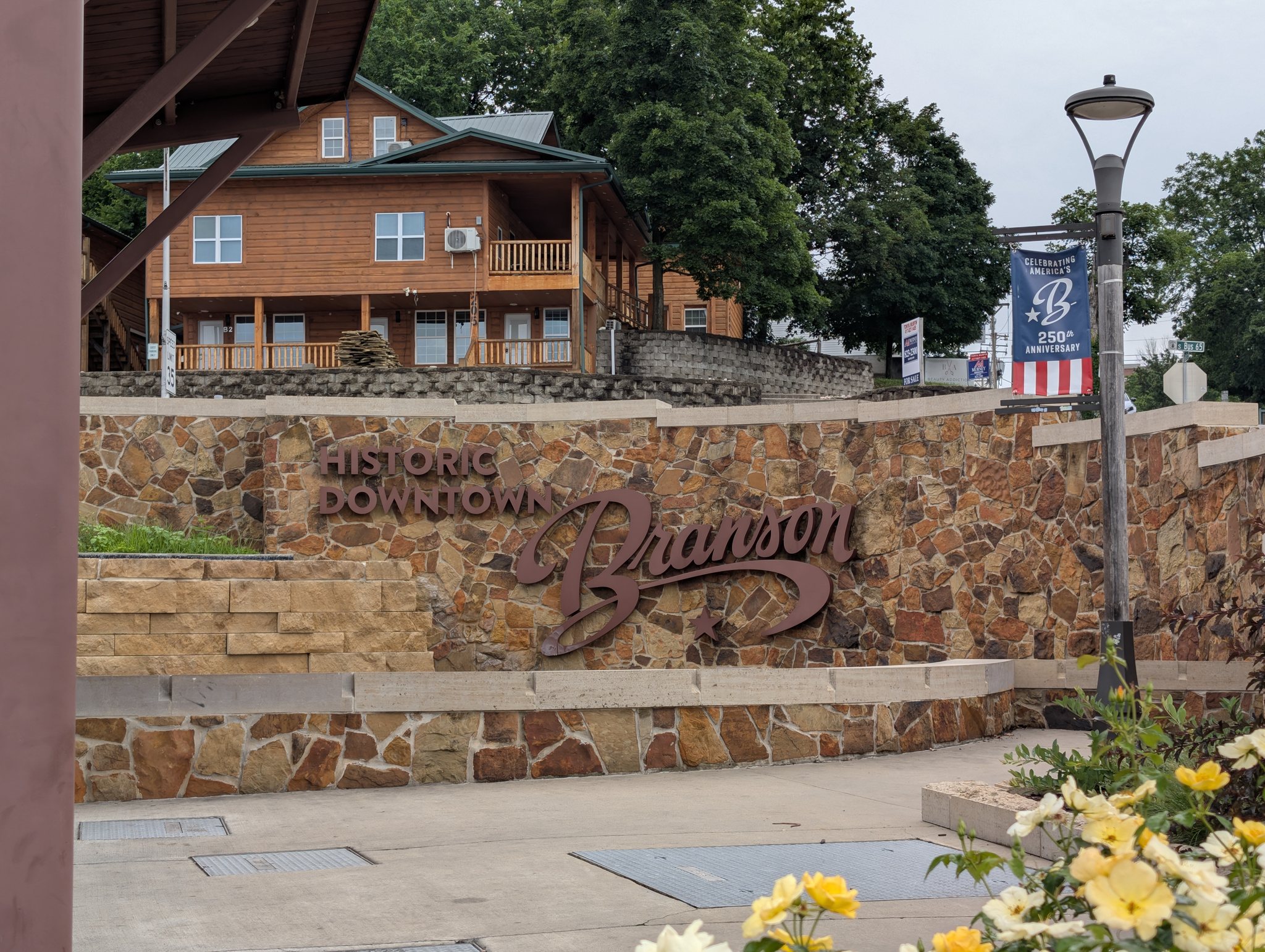 Historic Downtown Branson stone landmark sign with yellow roses