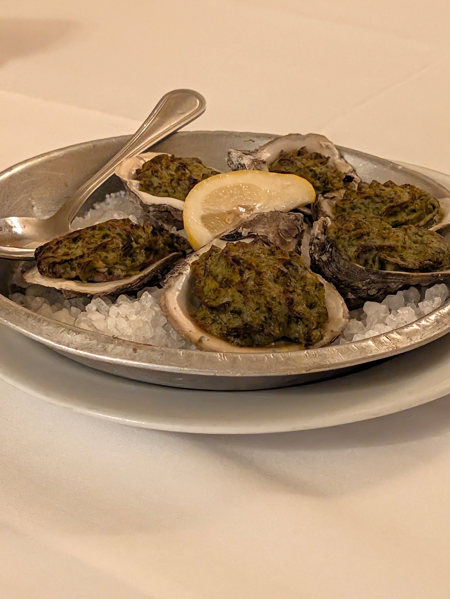 Baked oysters on the half shell with a lemon wedge on a platter at Antoine's in New Orleans