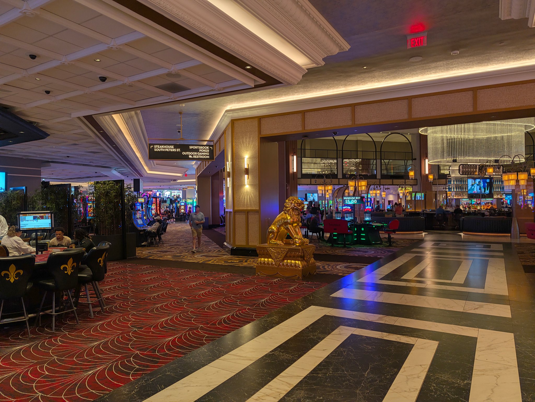 Casino floor at Caesars New Orleans with a gold lion statue, table games and slot machines