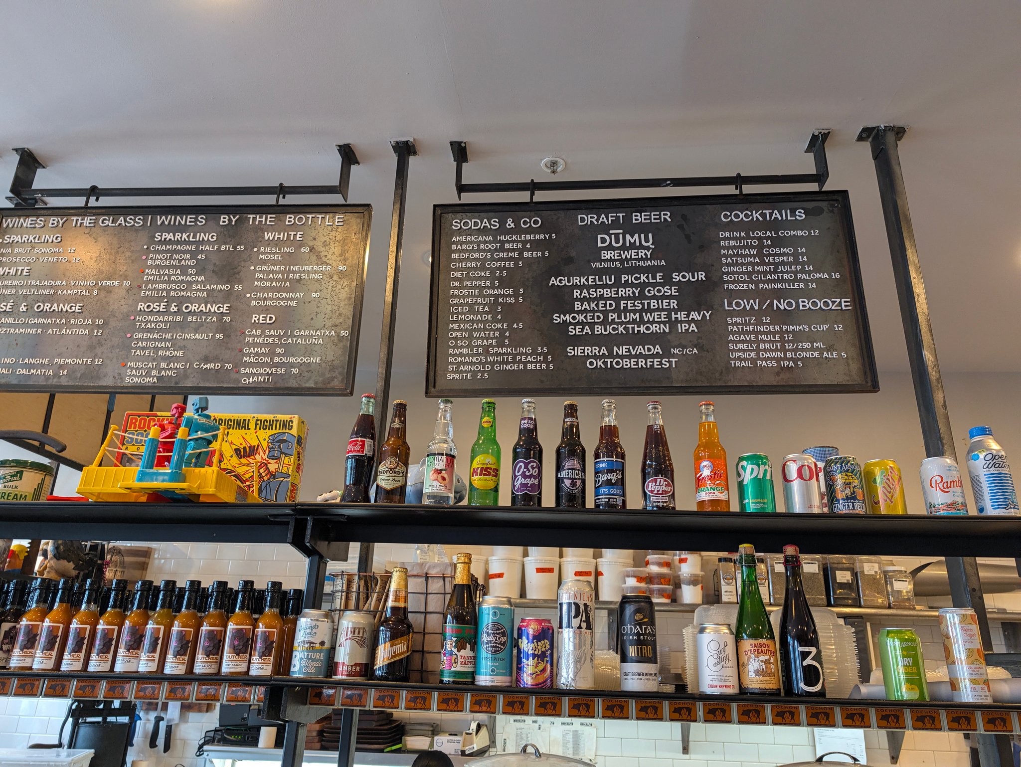 Counter at Cochon Butcher in New Orleans with chalkboard menus above a wall of bottles and hot sauces