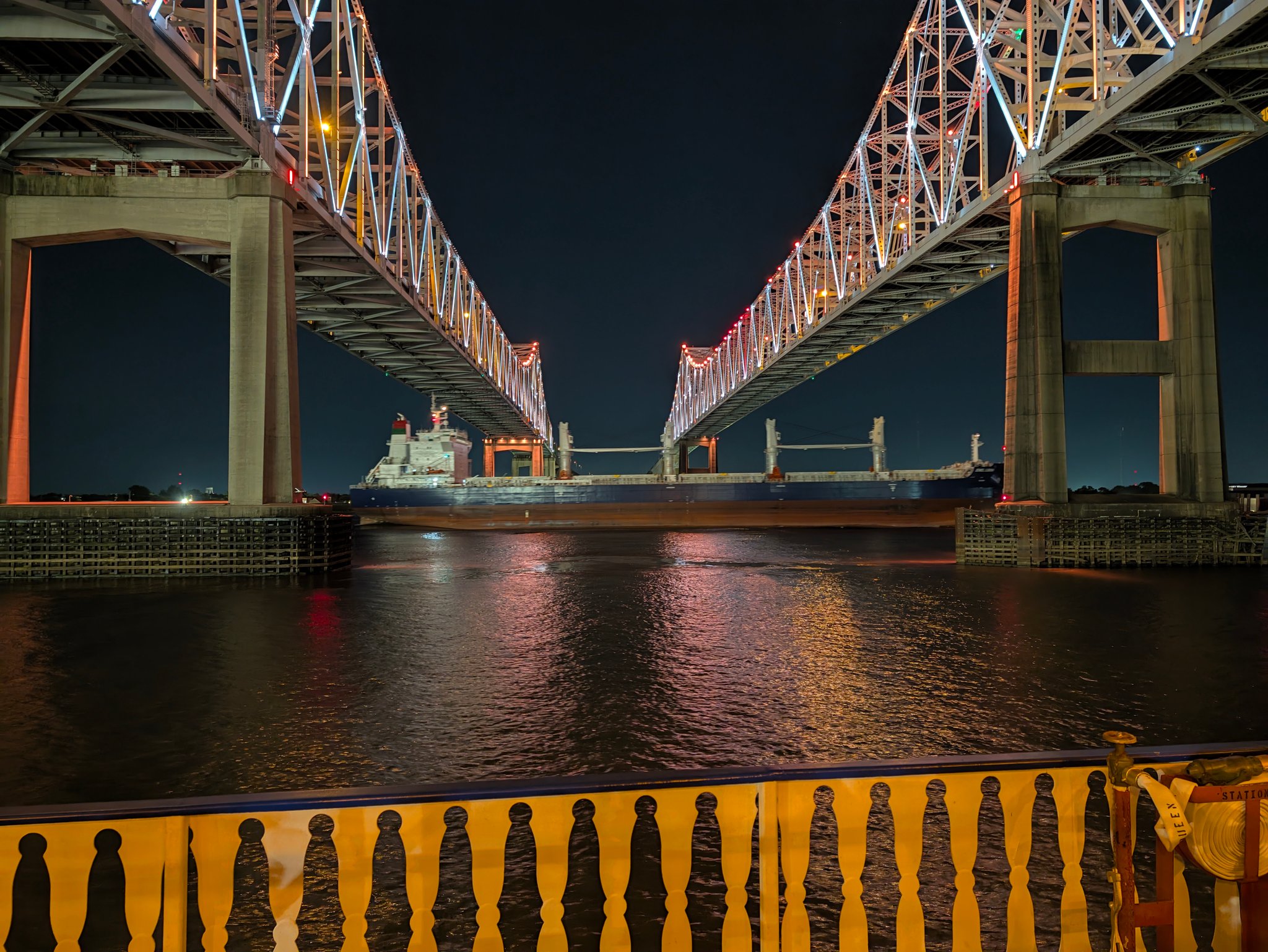 Lit steel truss bridge over the Mississippi River at night, seen from the Creole Queen cruise in New Orleans