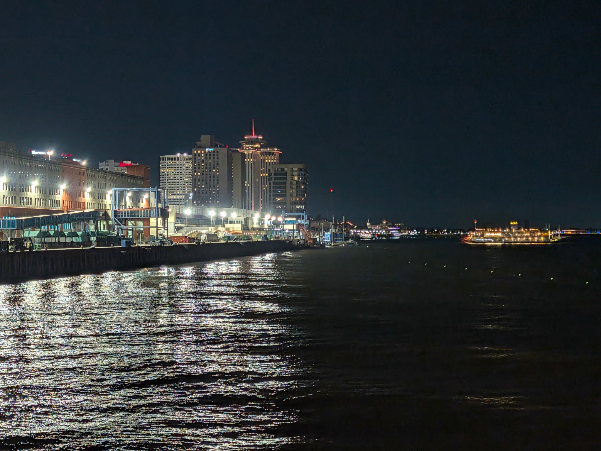 New Orleans skyline lit up at night across the Mississippi River, seen from the Creole Queen cruise