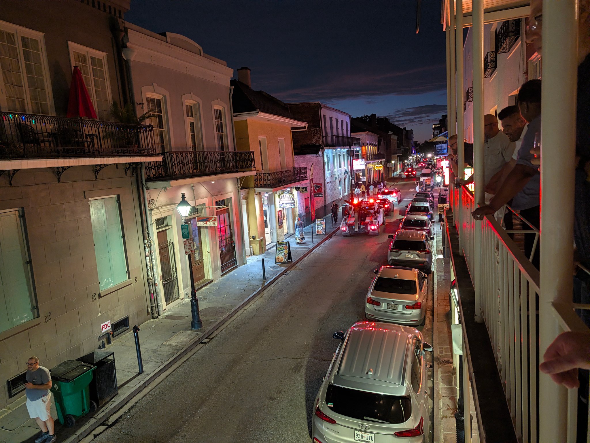 French Quarter street at night in New Orleans with iron balconies, neon signs and parked cars