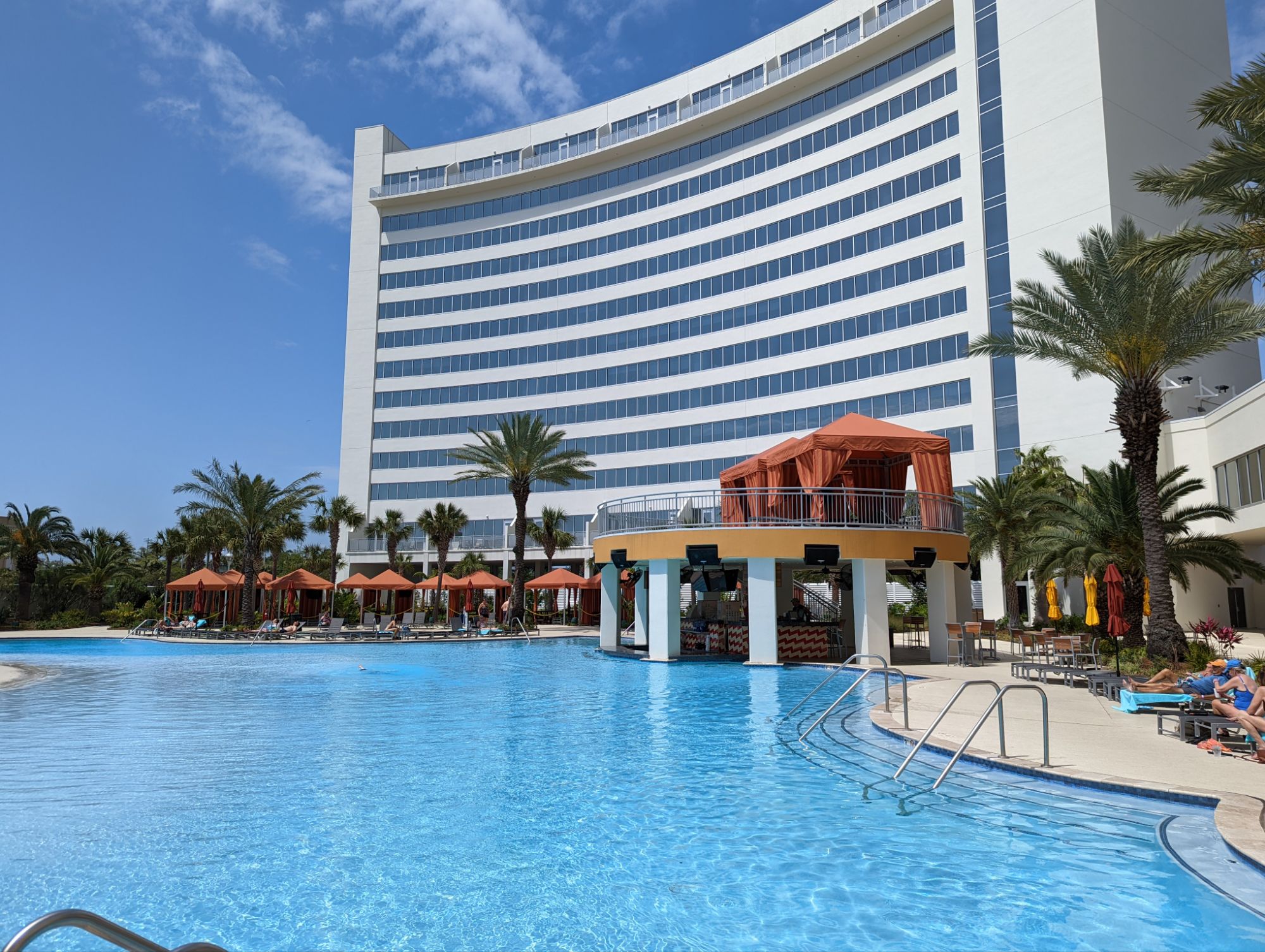 Hard Rock Biloxi pool with its circular swim-up bar under orange canopies and the hotel tower behind